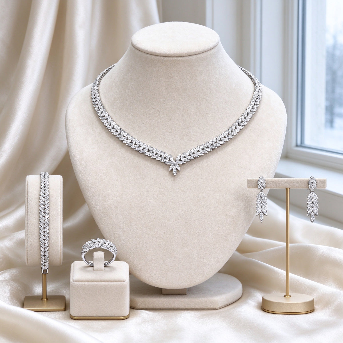 The Gardenia Wedding Suite silver-tone cubic zirconia laurel leaf V-chevron necklace, earrings, bracelet and ring on an ivory velvet bust
