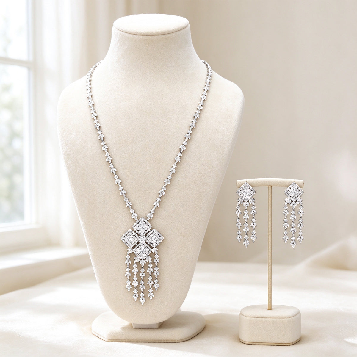 The Aster Bridal Set — silver-tone cubic zirconia Y-necklace with four-quad tassel pendant and matching drop earrings on ivory velvet bust