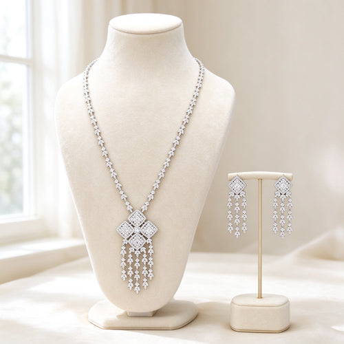 The Aster Bridal Set — silver-tone cubic zirconia Y-necklace with four-quad tassel pendant and matching drop earrings on ivory velvet bust