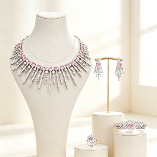 The Amara Wedding Parure — silver-tone sunburst fringe collar necklace, fringe earrings, pavé bracelet and cluster ring in pink CZ on an ivory background