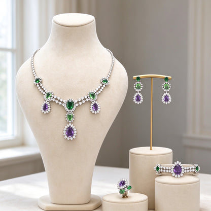 The Crown Crystal Parure silver-tone green and purple CZ four-piece necklace, earrings, brooch and ring on ivory velvet bust