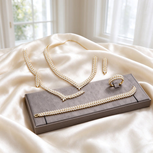 The Daybreak Wedding Suite gold-tone V-chevron marquise-CZ laurel necklace, long tapered leaf drop earrings, marquise tennis bracelet and marquise band ring on warm ivory silk