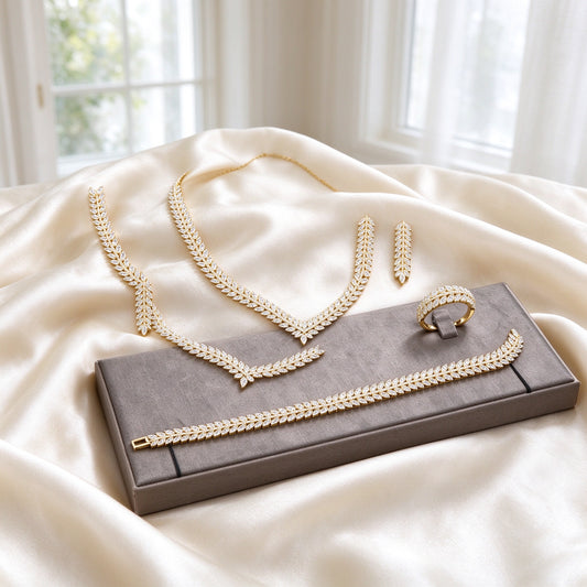 The Daybreak Wedding Suite gold-tone V-chevron marquise-CZ laurel necklace, long tapered leaf drop earrings, marquise tennis bracelet and marquise band ring on warm ivory silk
