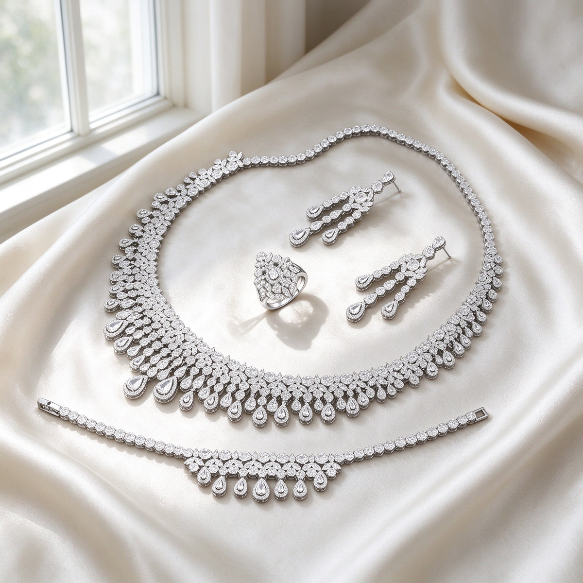 The Moonlight Bridal Set silver-tone pavé collar necklace with graduating pear-cut teardrop fringe, drop earrings, tennis bracelet and pear-cluster ring on ivory silk