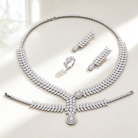 The Cordelia Wedding Suite — silver-tone graduated marquise-leaf pavé collar necklace with double-halo pear pendant, leaf-drop earrings, bracelet and ring on an ivory background