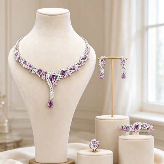 The Nova Bridal Parure - silver-tone pink-to-purple gradient CZ Y-necklace with long pear pendant on an ivory bust, with earrings, bracelet and ring