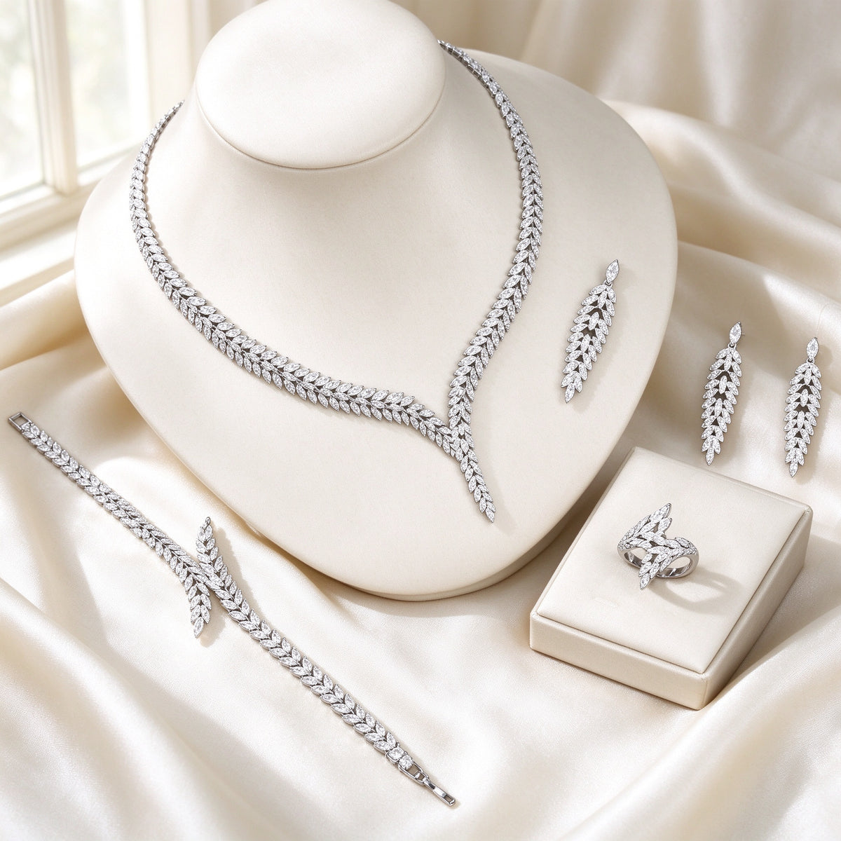 The Elowen Wedding Suite — silver-tone laurel-branch V-necklace, cascading leaf earrings, leafy tennis bracelet and crossing-branch ring on ivory silk