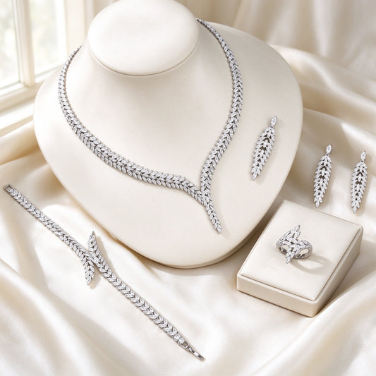 The Elowen Wedding Suite — silver-tone laurel-branch V-necklace, cascading leaf earrings, leafy tennis bracelet and crossing-branch ring on ivory silk
