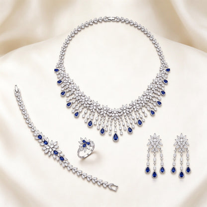 The Finley Bridal Parure – silver-tone pavé CZ floral bib necklace, chandelier earrings, bracelet and ring with sapphire-blue pear drops on ivory silk