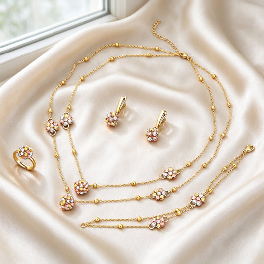 The Sunbeam Crystal Parure dainty gold-tone layered ball-bead chains dressed with tri-color three-dimensional flowers, lever-back earrings, flower charm bracelet and flower ring on warm cream silk