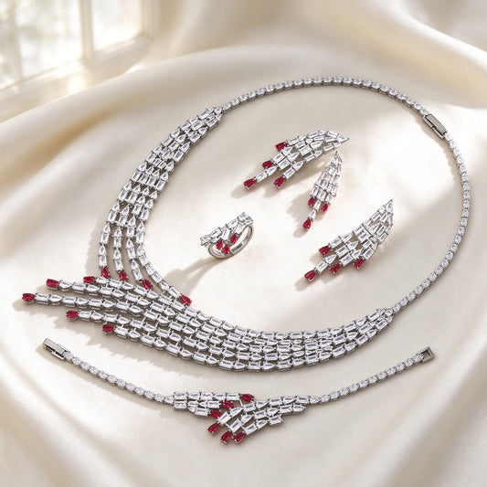 The Maeve Bridal Parure — silver-tone art-deco baguette-CZ draped waterfall necklace, chandelier earrings, bracelet and V-ring with ruby-red pear drops on ivory silk