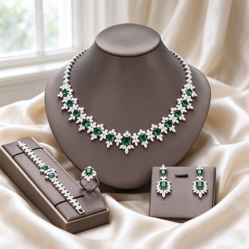 The Twilight Bridal Parure silver-tone fringe collar necklace with emerald-green emerald-cut CZ and clear halos, drop earrings, tennis bracelet and halo cluster ring on warm cream silk