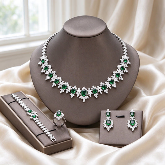 The Twilight Bridal Parure silver-tone fringe collar necklace with emerald-green emerald-cut CZ and clear halos, drop earrings, tennis bracelet and halo cluster ring on warm cream silk