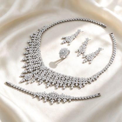 The Selene Bridal Parure — silver-tone pavé botanical fringe collar necklace, chandelier drop earrings, fringe bracelet and leaf-cluster ring on ivory silk
