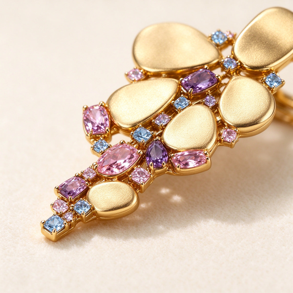 The Aurelia Bridal Set – macro of brushed gold pebble discs and faceted pink, lavender and blue cubic zirconia
