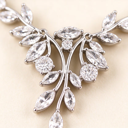 Macro close-up of marquise-cut leaf-shaped cubic zirconia and round berry CZ on a silver-tone branch