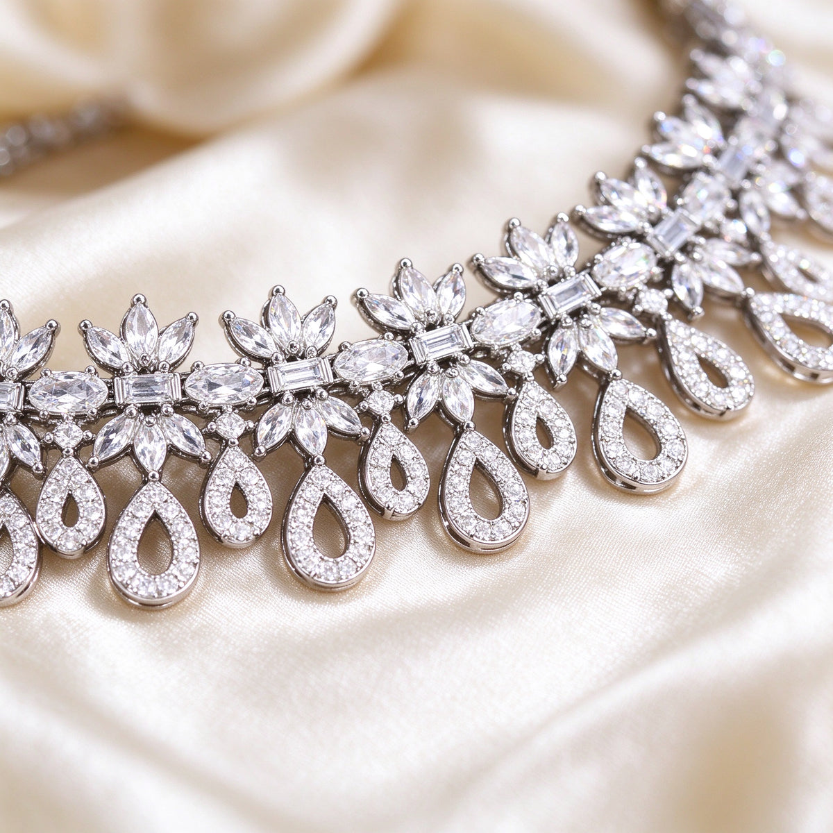Macro of ornate floral CZ clusters with open teardrop pavé frames on silk