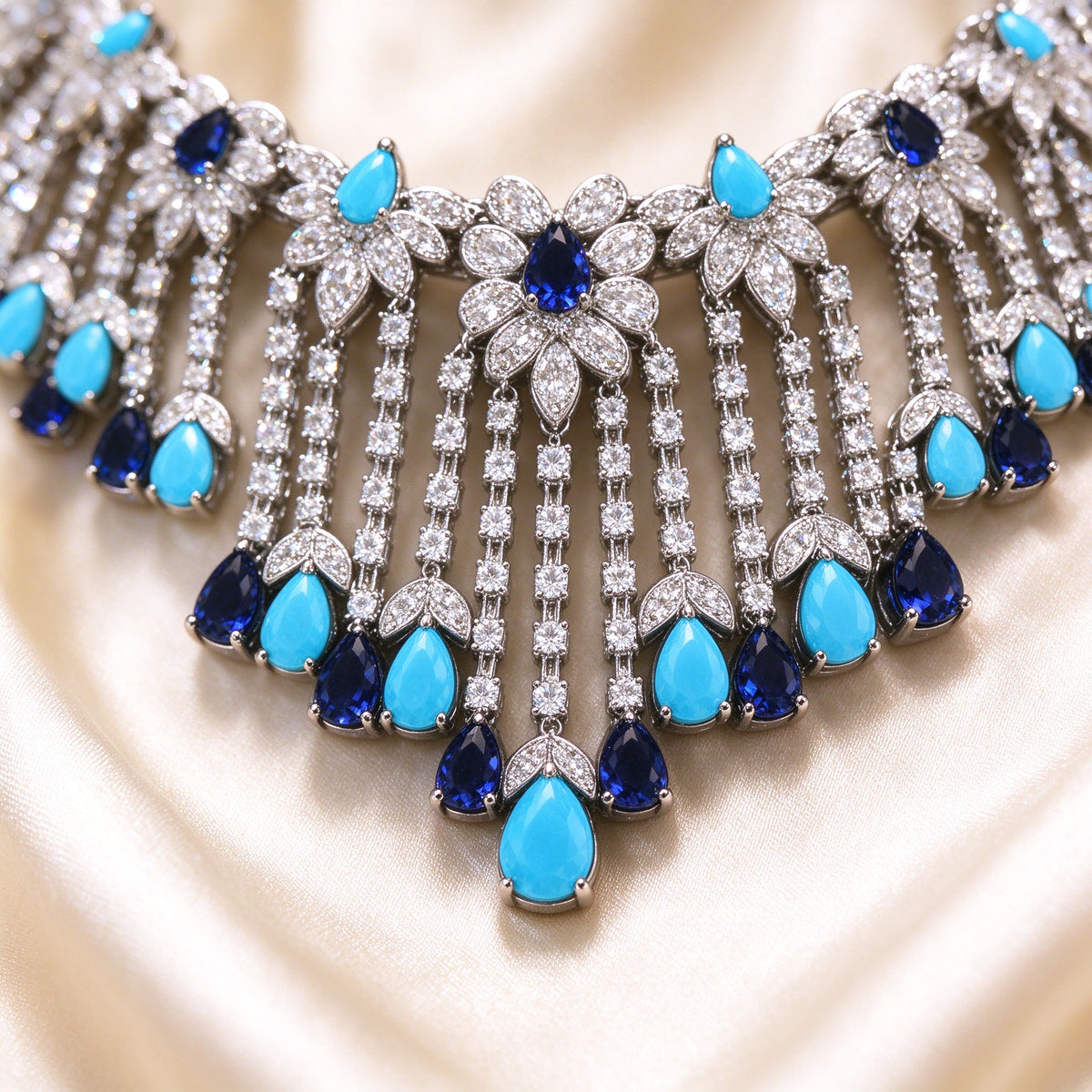 Macro detail of pavé CZ floral clusters and turquoise-navy pear-shaped drops on cream silk