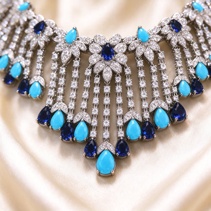 Macro detail of pavé CZ floral clusters and turquoise-navy pear-shaped drops on cream silk