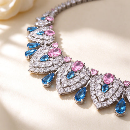 Macro close-up of The Wren clear-CZ teardrop panels centered with rose-pink and azure-blue stones on ivory silk