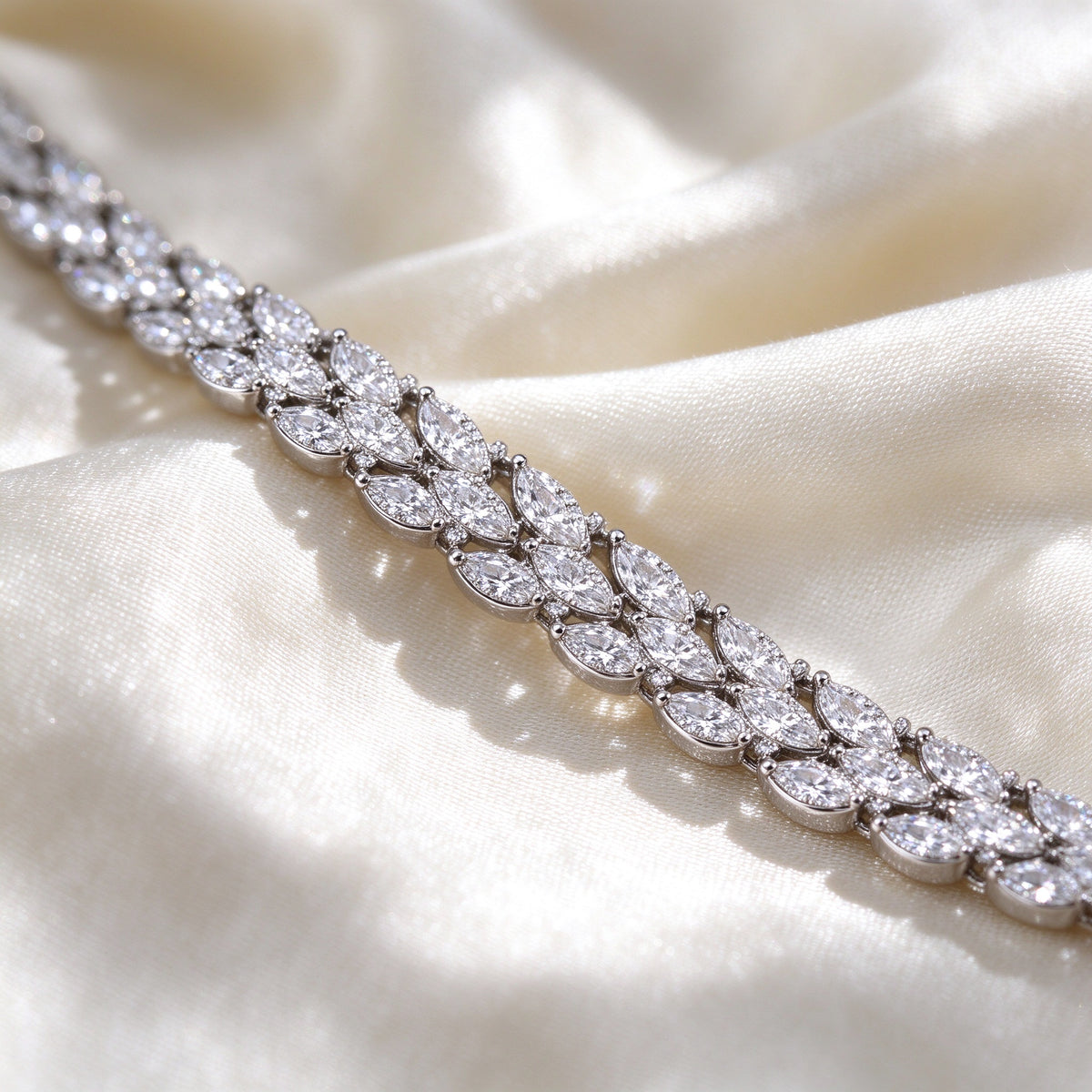 Macro of The Thorn Wedding Suite interlocking marquise-leaf CZ links woven into a continuous glittering vine on ivory silk