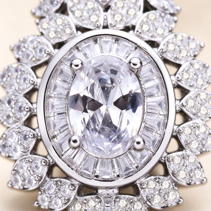 Macro close-up of an oval clear cubic zirconia surrounded by a baguette-cut halo and marquise-leaf CZ