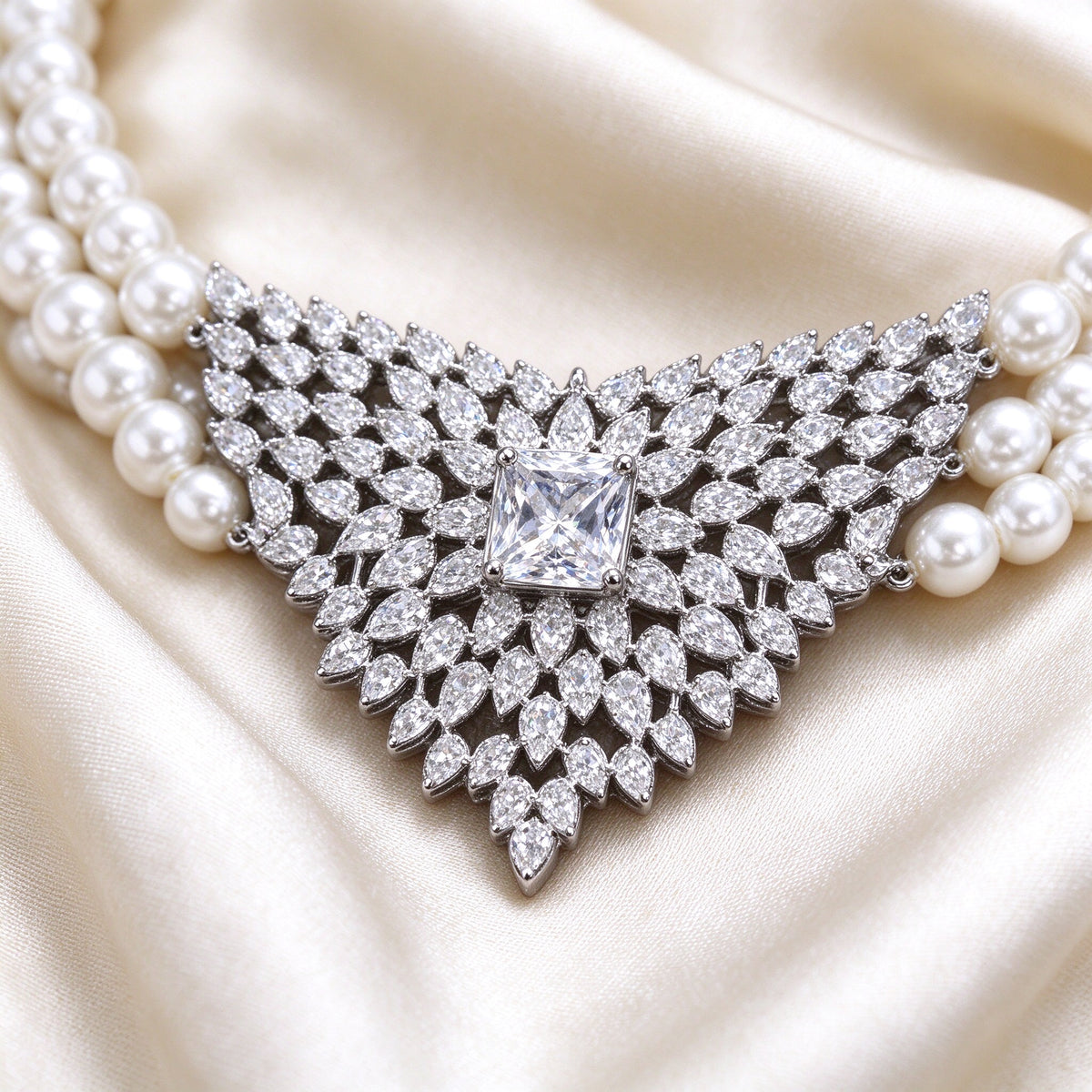 Macro detail of The Vale Bridal Parure V-shaped CZ pendant on pearl necklace