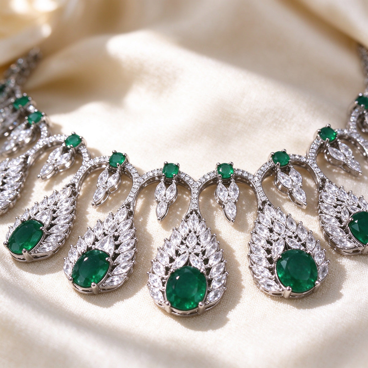 Macro detail of The Zinnia Bridal Parure fringe collar necklace showing leaf CZ frames around green oval stones