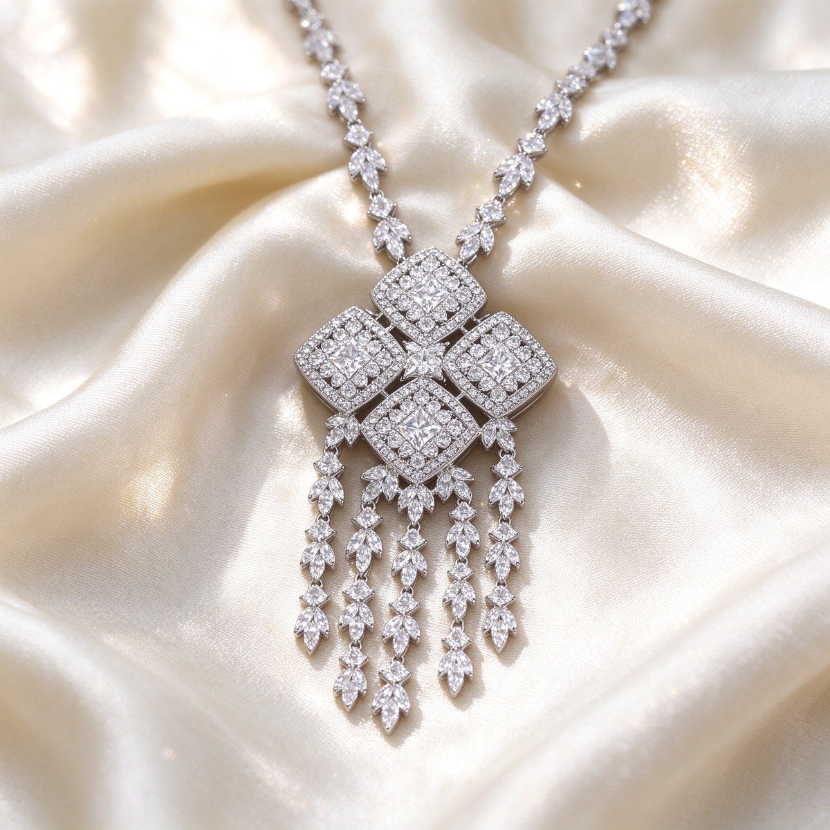 Macro of The Aster four-quad CZ cluster pendant with five tassel fringe strands on ivory silk fabric