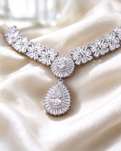 Macro of baguette-cut sunburst clusters and pear-cut halo pendant in silver-tone