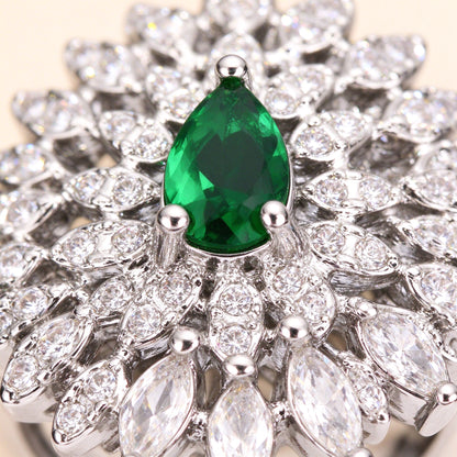 Macro close-up of an emerald green pear-shaped cubic zirconia surrounded by radiating clear marquise CZ petals