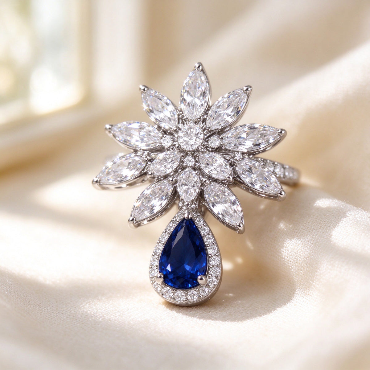 The Finley Bridal Parure – macro of pavé CZ marquise starburst cluster framing a sapphire-blue pear-shaped drop