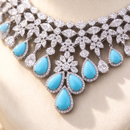 Macro close-up of a turquoise pear-shaped cubic zirconia drop surrounded by clear CZ floral clusters