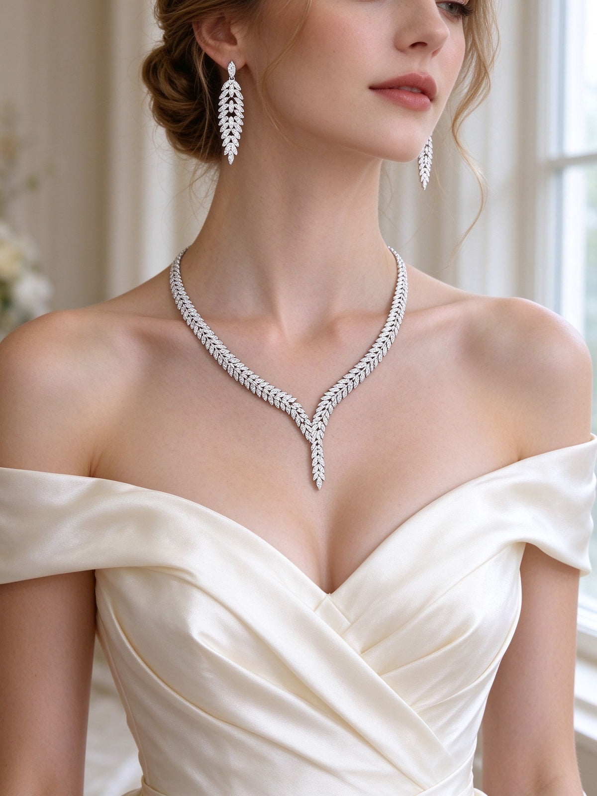 Bride in an ivory off-shoulder gown wearing The Elowen Wedding Suite V-neck laurel necklace and cascading leaf earrings
