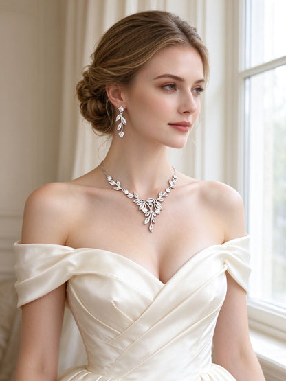 Bride in an ivory off-shoulder silk gown wearing The Delaney Wedding Suite leaf branch necklace and linear drop earrings