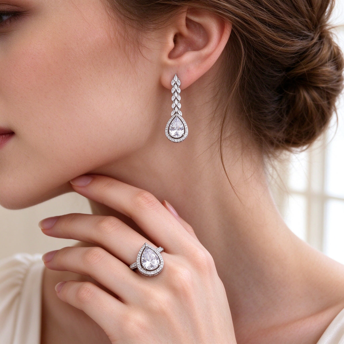 Close-up of pear-cut CZ teardrop drop earrings and halo ring