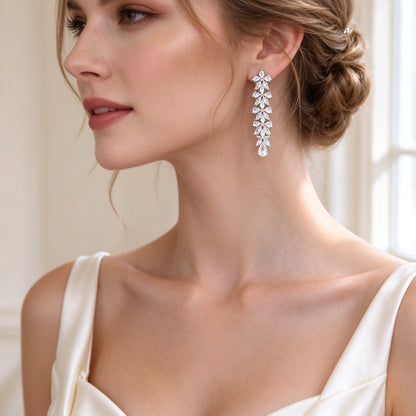 Close-up of The Crest long linear marquise-and-pear CZ drop earrings on a bride