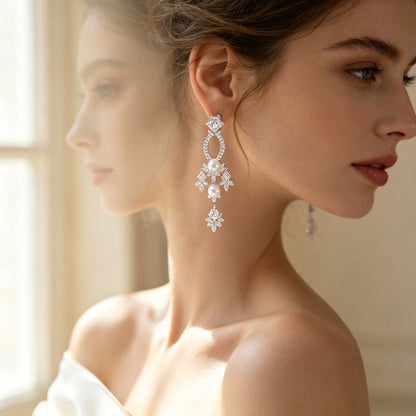 Close-up of oval-frame pearl chandelier CZ drop earrings worn by a bride