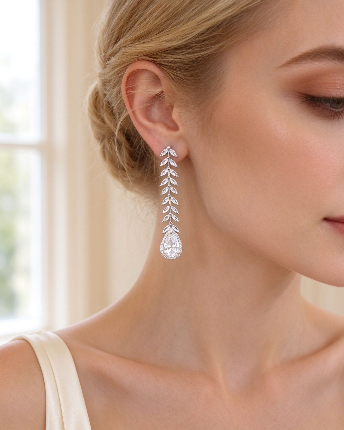 Close-up of the leaf-stem teardrop CZ drop earrings on a bride