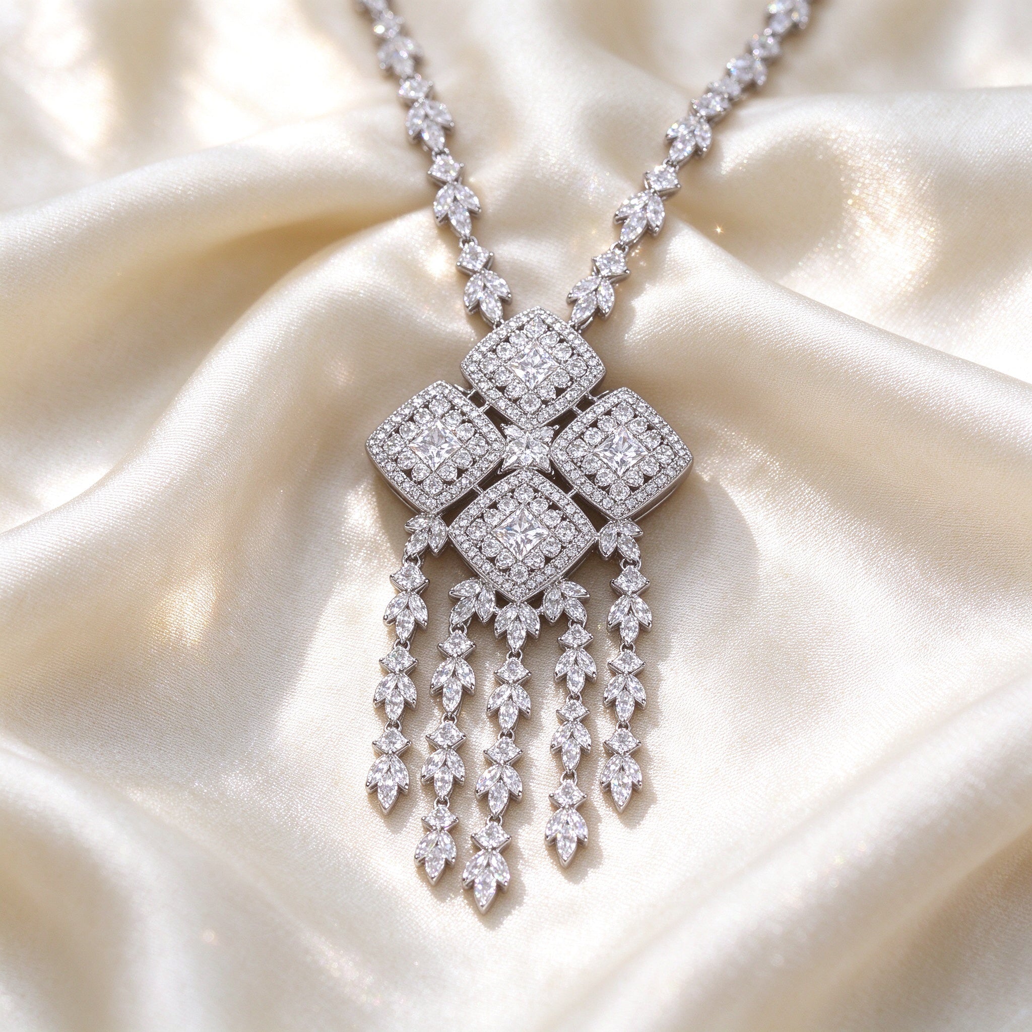 Macro of The Aster four-quad CZ cluster pendant with five tassel fringe strands on ivory silk fabric