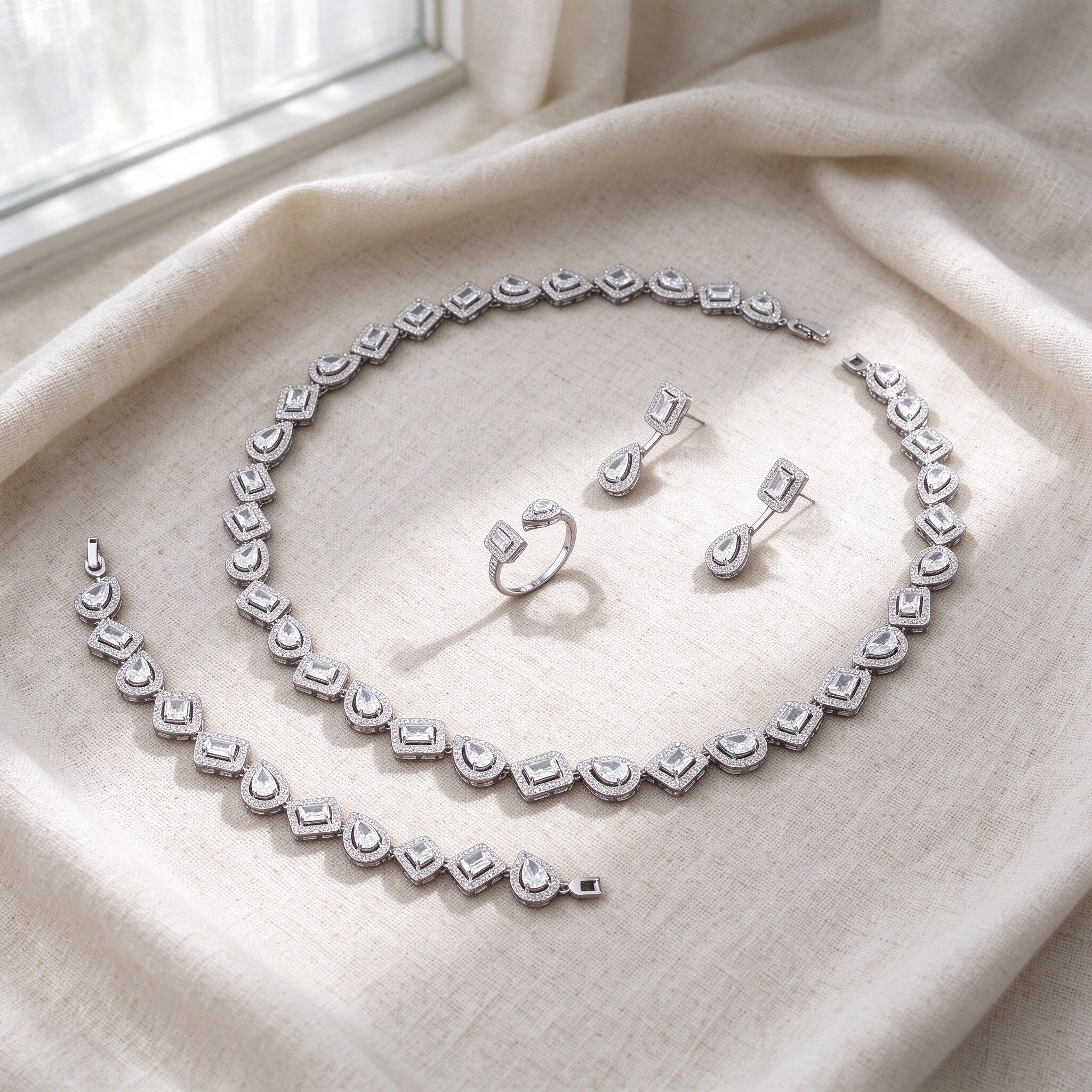 Top-down flat lay of The Celestia Wedding Suite four-piece halo CZ bridal set on warm ivory linen