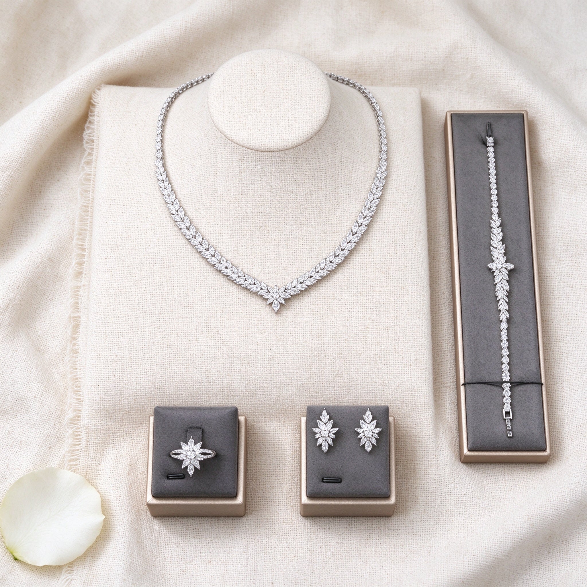 Top-down flat lay of The Coronet Bridal Set four-piece clear CZ leaf bridal set on ivory linen