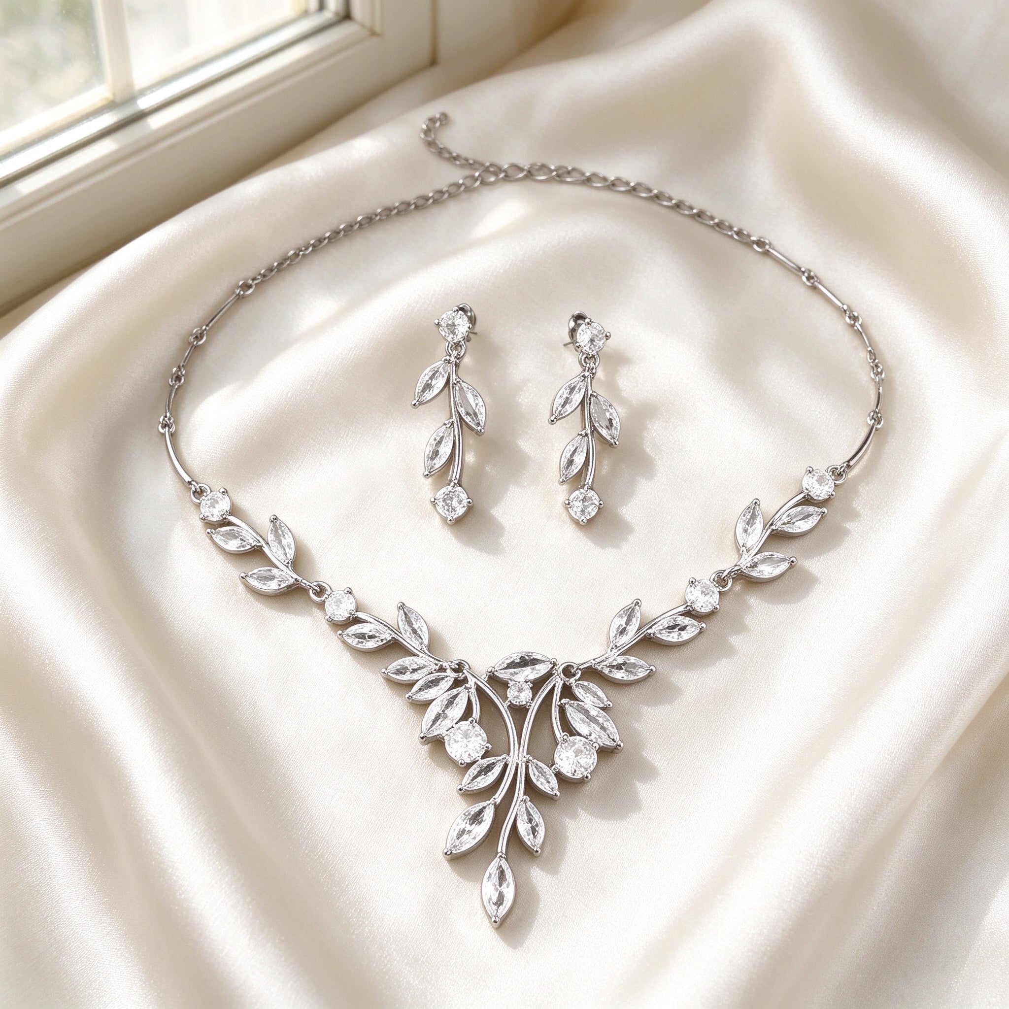 Flat lay of The Delaney Wedding Suite two-piece necklace and earrings on ivory silk satin