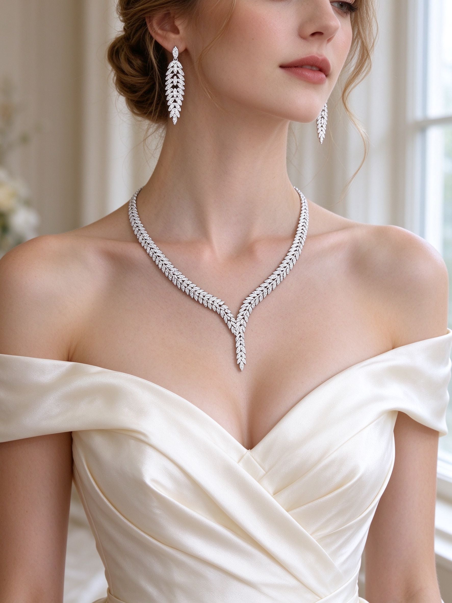 Bride in an ivory off-shoulder gown wearing The Elowen Wedding Suite V-neck laurel necklace and cascading leaf earrings