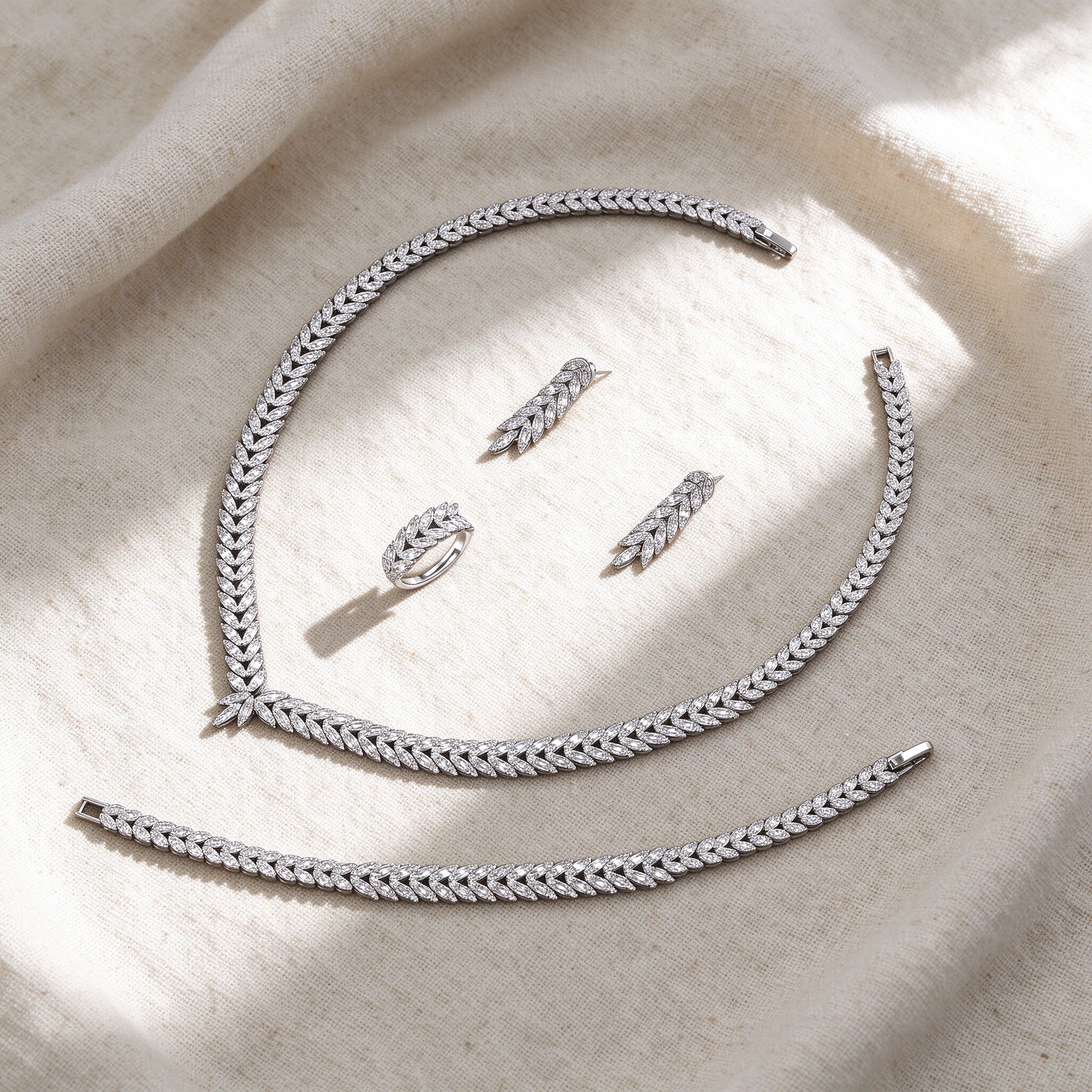 Flat lay of the silver CZ laurel leaf four-piece bridal set on cream linen
