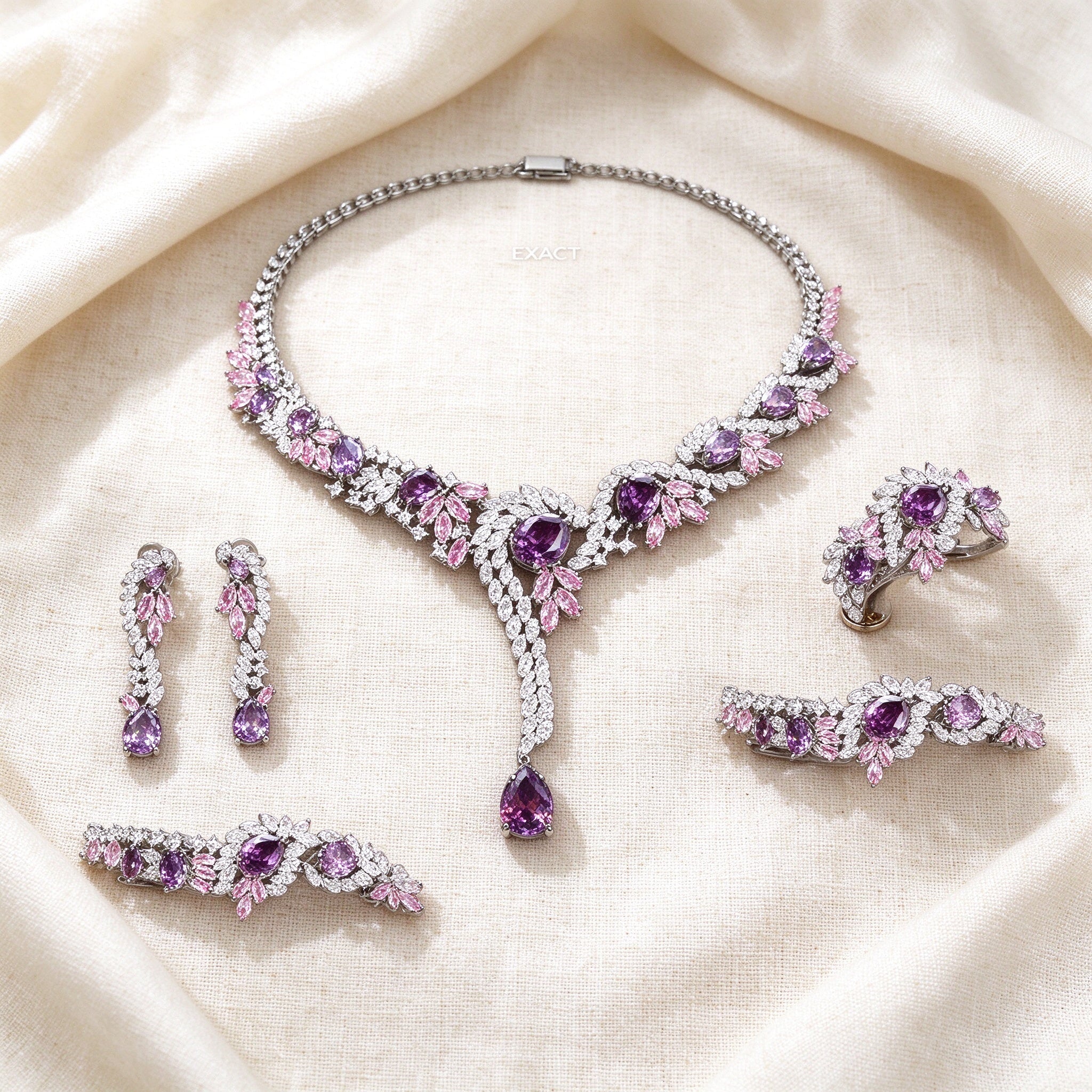 Flat lay of The Nova Bridal Parure necklace, tiered drop earrings, cluster bracelet and ring on ivory linen
