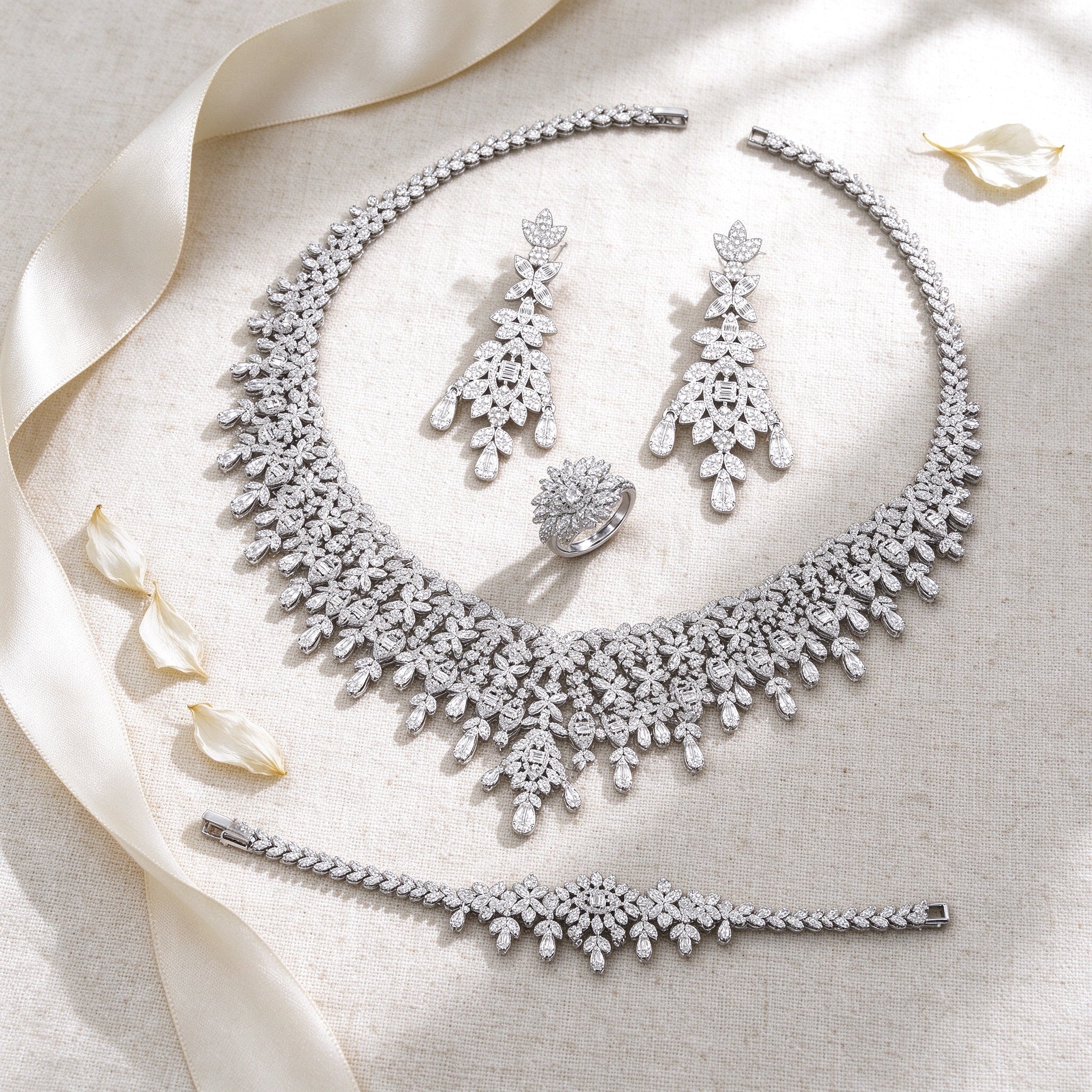 Styled flat lay of The Selene Bridal Parure necklace, earrings, bracelet and ring on cream linen with an ivory ribbon